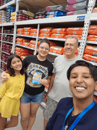 a group of people posing for a picture in front of a shelf full of dog food