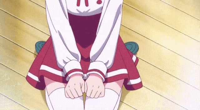 a girl in a red and white skirt is kneeling down with her hands folded