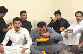 a group of men are sitting on the floor eating and drinking