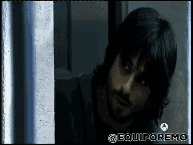 a man with long hair and a beard is looking out a window with the hashtag @equiporemo