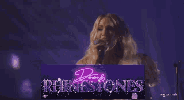 a woman singing into a microphone in front of a banner that says amazon music