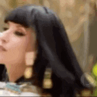a woman with long black hair and earrings is wearing a costume .