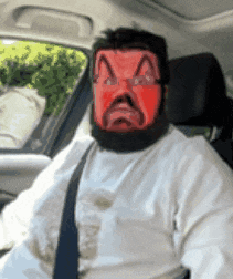 a man wearing a red mask is sitting in the driver 's seat of a car