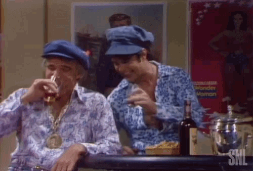 two men are sitting at a bar with a bottle of wine and a poster that says snl