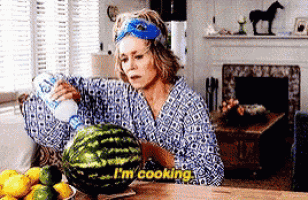 a woman is cutting a watermelon and saying i 'm cooking