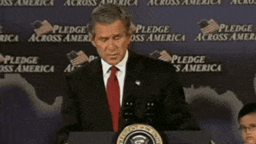 a man in a suit and tie stands at a podium with the words grief me on the bottom