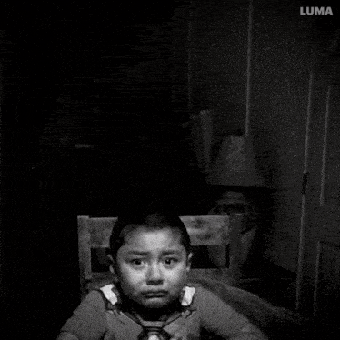 a black and white photo of a young boy with a lamp in the background and a watermark that says jmn