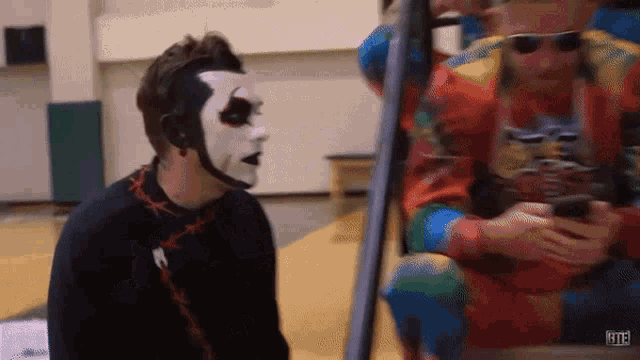 a man with a mask on his face is standing next to a man wearing sunglasses