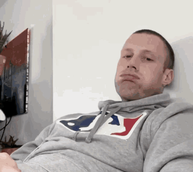 a man wearing a gray hoodie with the letter a on it