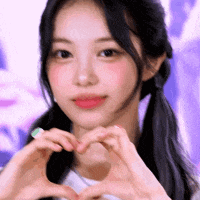 a young woman is making a heart with her hands .