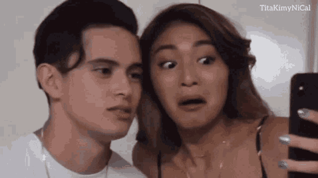 a man and a woman are taking a selfie together . the woman is making a funny face .