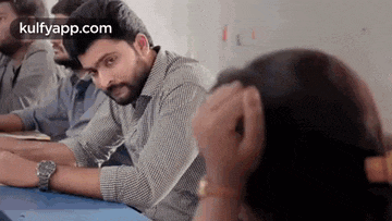 a man and a woman are sitting at a desk in a classroom .