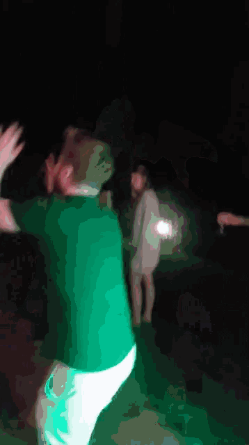 a man in a green shirt is dancing with a woman in a white dress