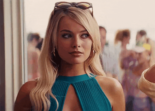 a woman wearing sunglasses and a blue top is standing in front of a window .