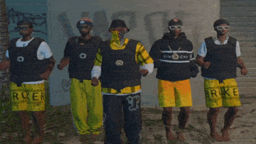 a group of men standing in front of a wall with one wearing a shirt that says givenchy