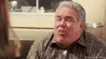 a man in a plaid shirt is sitting at a table talking to another man .