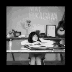 a black and white photo of a girl sitting at a desk with the name mai fukagawa on the wall
