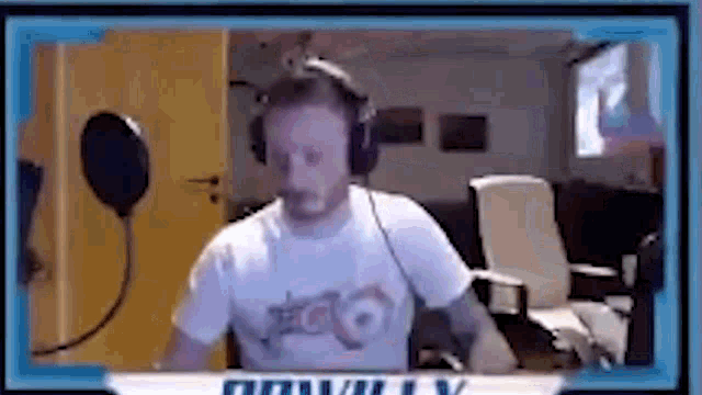 a man wearing headphones is sitting in front of a microphone on a computer screen .
