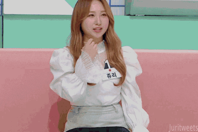 a girl is sitting on a pink couch with korean writing on the bottom