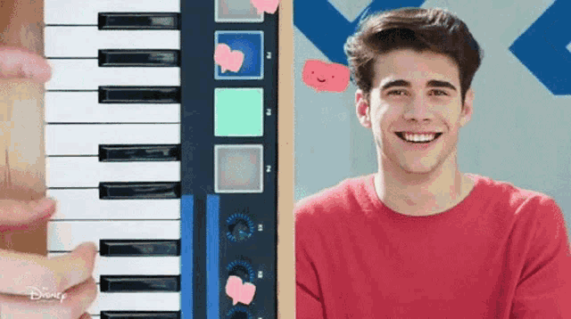 a young man in a red shirt is smiling while playing a piano keyboard .