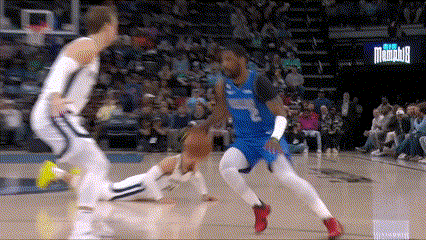 two basketball players are playing a game of basketball on a court with a crowd in the stands watching .
