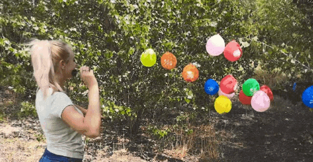 a woman is blowing up balloons in the woods and one of the balloons says " i love you "