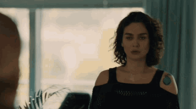 a woman with a tattoo on her shoulder is looking at a man