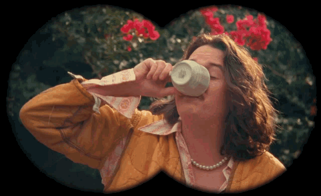 a man with a pearl necklace is drinking out of a cup