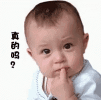 a baby is holding his finger to his mouth .