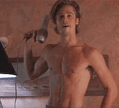 a shirtless man is holding a hair dryer in his hand in front of a lamp .