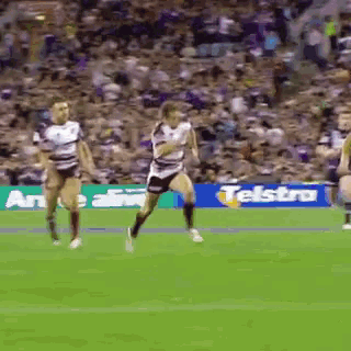 a rugby game is being played on a field with a telstra banner in the background