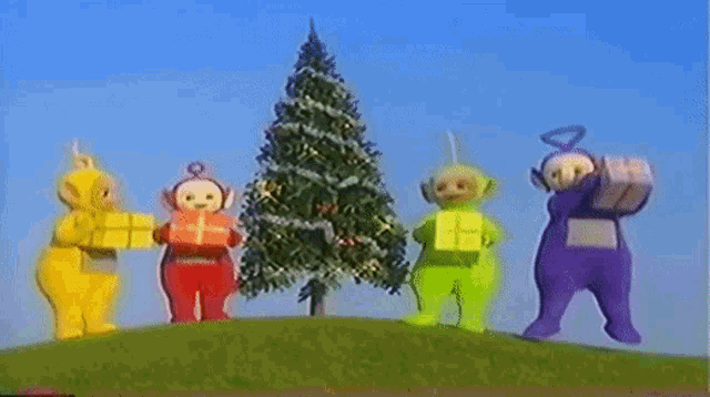 a group of teletubbies are standing next to a christmas tree