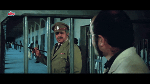 a man in a military uniform stands in front of a prison cell with a sign that says ultra on it