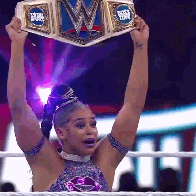 a woman in a wrestling ring is holding up a wrestling championship belt