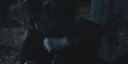 a man and a woman are hugging in a dark room .