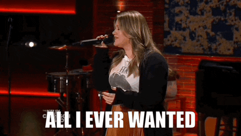 a woman singing into a microphone with the words " all i ever wanted " behind her