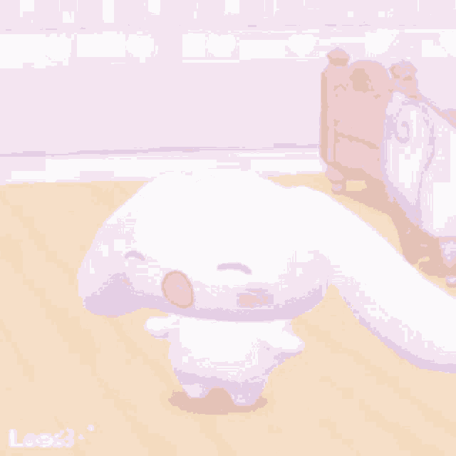 a white bunny is standing on a wooden floor in a room with a pink nightstand in the background .