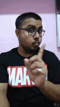 a man wearing glasses and a black shirt that says marvel on it
