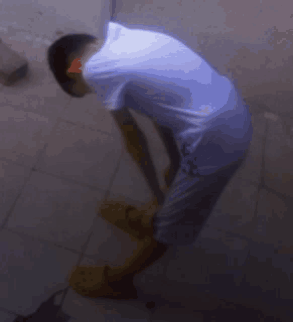a man in a white shirt and blue shorts is kneeling down on the floor