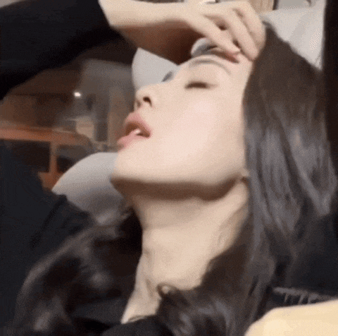 a woman is laying on a couch with her eyes closed and her hand on her forehead .