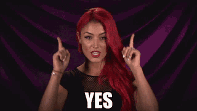 a woman with red hair is saying yes with her fingers