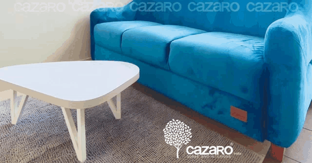 a blue couch sits next to a white coffee table with the words cazaro on the bottom