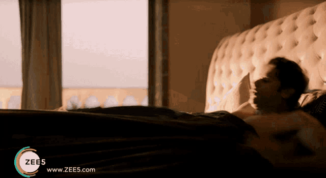 a man is laying on a bed with a zees logo on the bottom