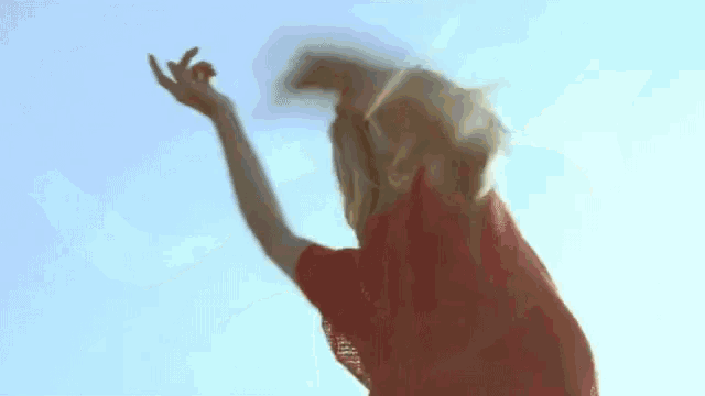 a woman in a red shirt is standing with her arms outstretched in the air .