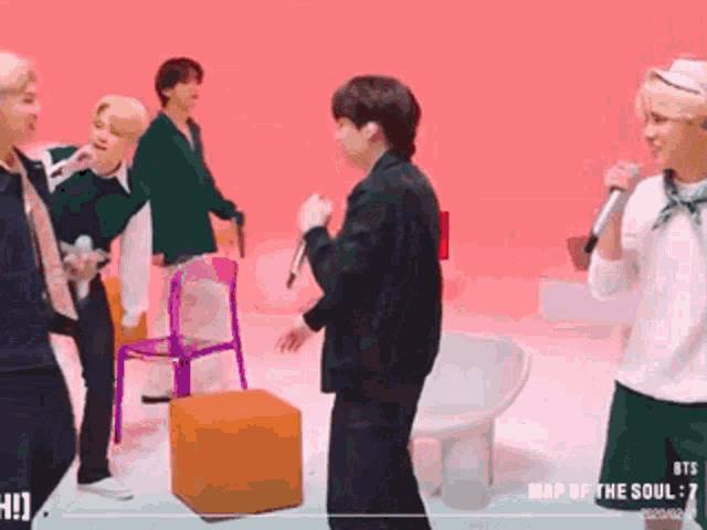 a group of people are standing in a room with a chair and a microphone .