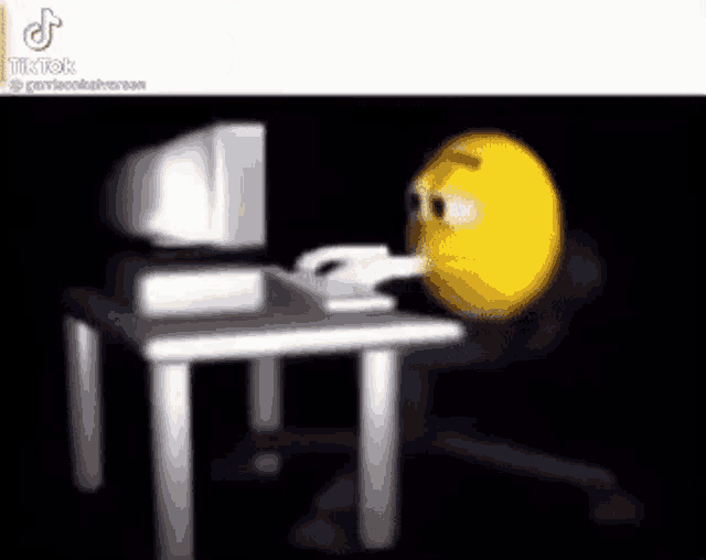 a cartoon smiley face is sitting at a desk using a computer .