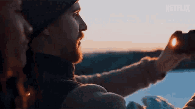 a man is taking a picture of the sun with binoculars while a woman looks on .