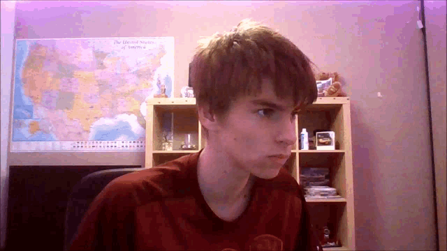 a young man is sitting in front of a map of the united states of america