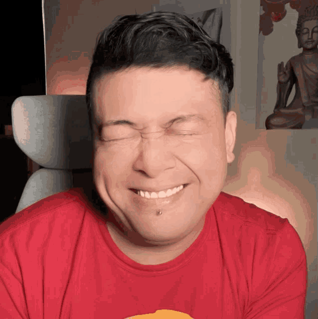 a man wearing a red shirt is making a funny face with his eyes closed