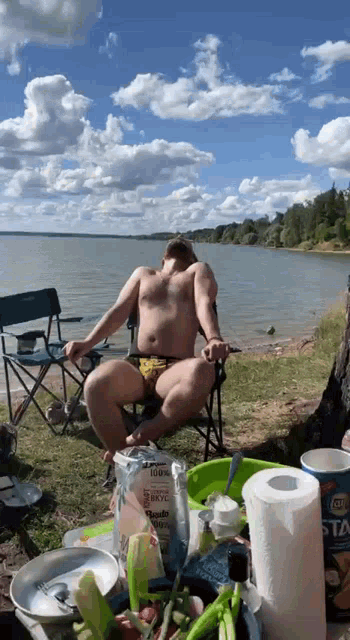 a man sits in a chair on the beach with a bag that says ' 100 % ' on it